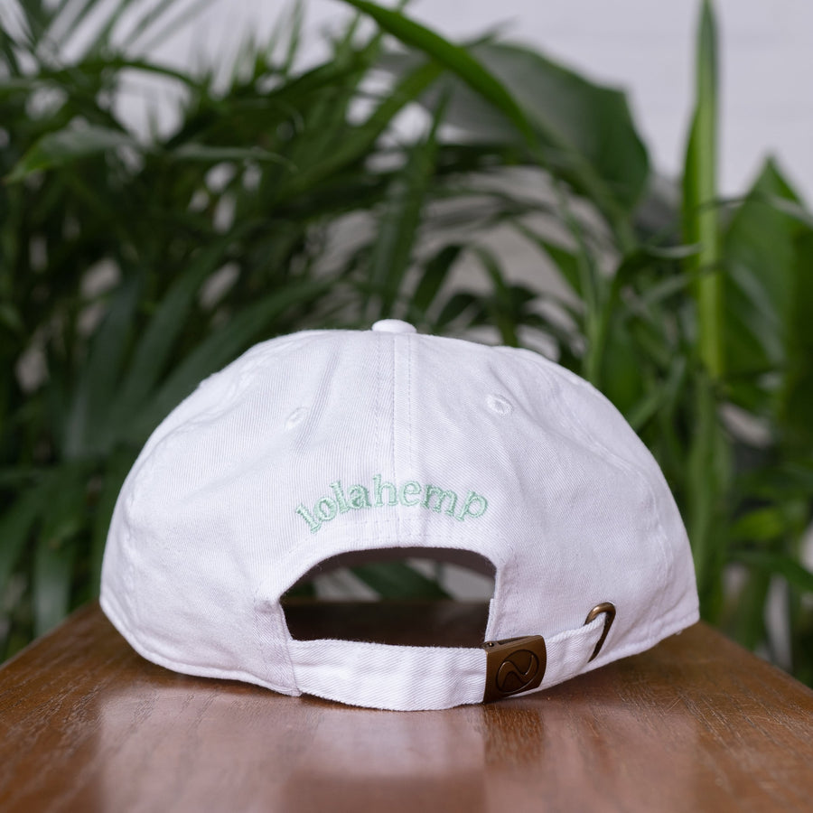 back of white lolahemp hat on wooden table with plants in the background