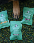 Front of mini green colored bags of regular strength lolahemp calming, hip & joint & omega hemp soft chews on green carpet with a dog paw in the center
